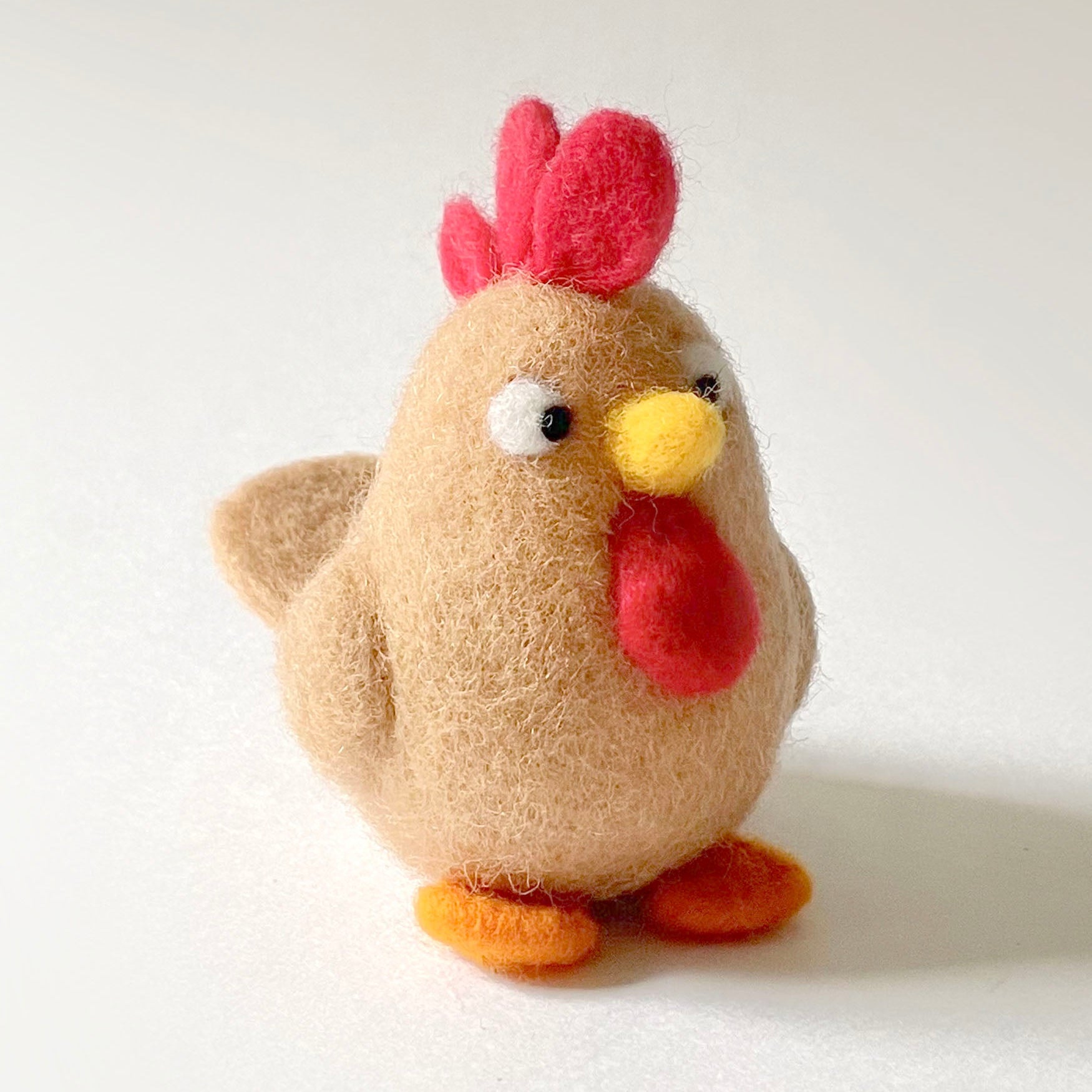 Stuffed rooster toy with a red comb on a white background