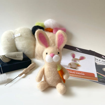 Felted rabbit toy with tools and instructions on a white surface