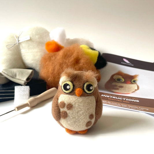 Plush owl toy with felting tools and instructions on a white background
