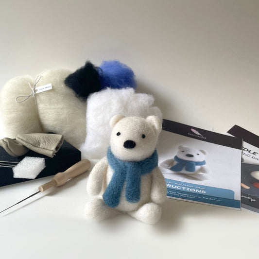 White plush polar bear with blue scarf and accessories on a white background
